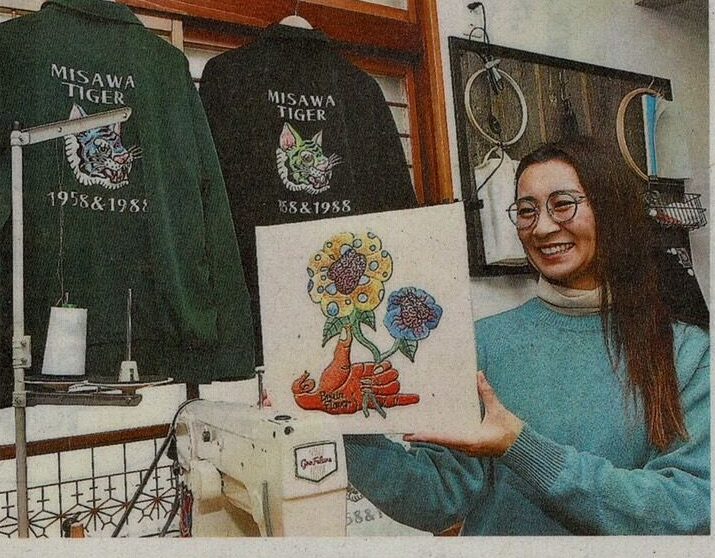 Newspaper, first solo exhibition, the artist holding an embroidered work (press)