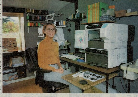 Newspaper feature, the artist at her embroidery machine (press)